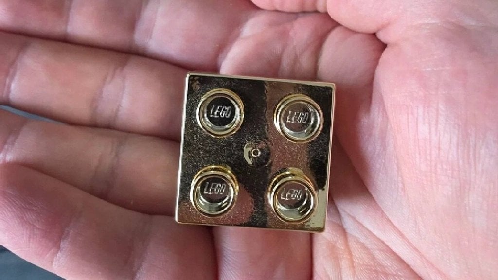 Un employé de LEGO montre ce qu&rsquo;il a reçu pour son quatrième anniversaire de travail : une brique Lego dorée que nous voulons tous avoir maintenant